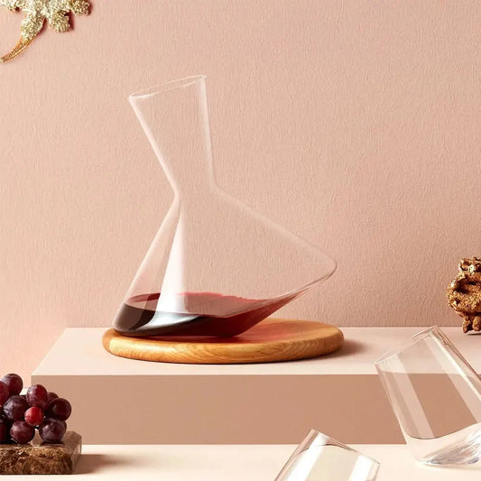 Carafe à vin Balance en cristal posée sur un support en bois, avec des verres à dégustation et des raisins en décoration.