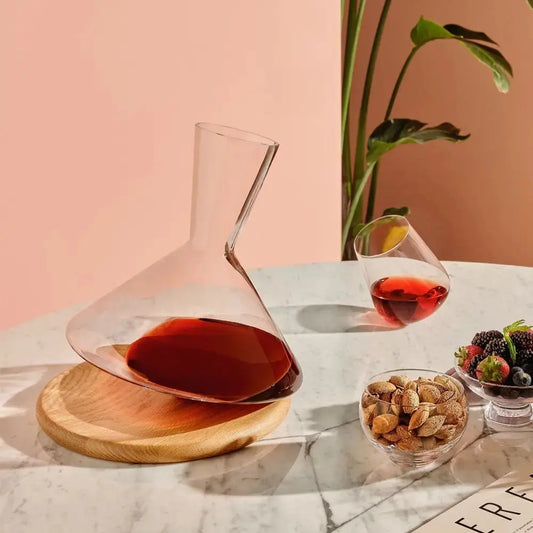 Carafe à vin Balance en cristal posée sur table en marbre, accompagnée d’un verre de vin et de fruits secs pour un moment de dégustation convivial.