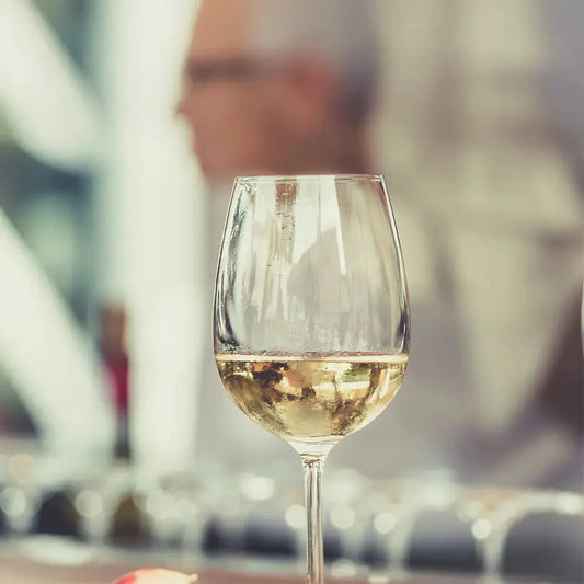 Verre à vin pour sauvignon blanc, mise en situation avec arrière-plan flou d’un homme en dégustation.