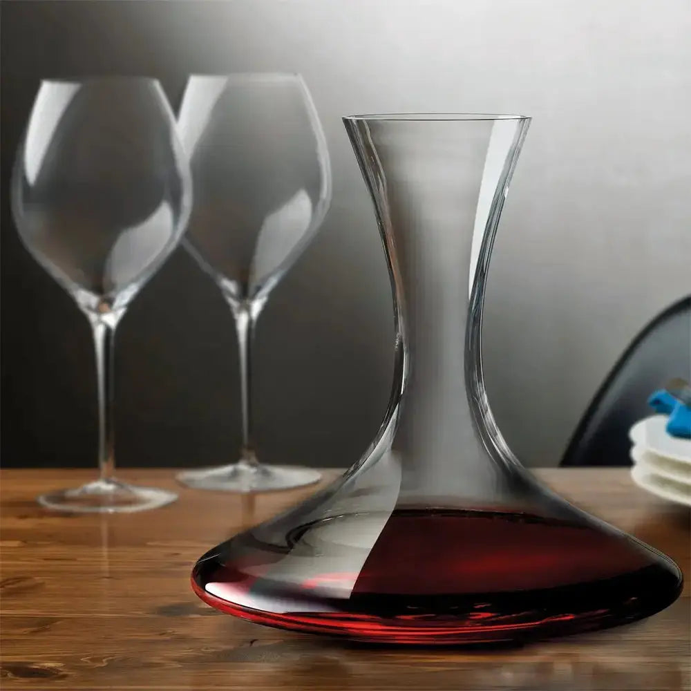 Carafe pour le vin bodega remplie de vin rouge. En second plan il y a deux verres de vin vides. 