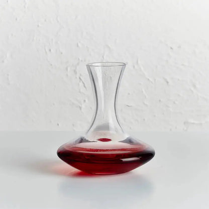 Carafe pour vin ego remplie de vin rouge sur fond blanc.