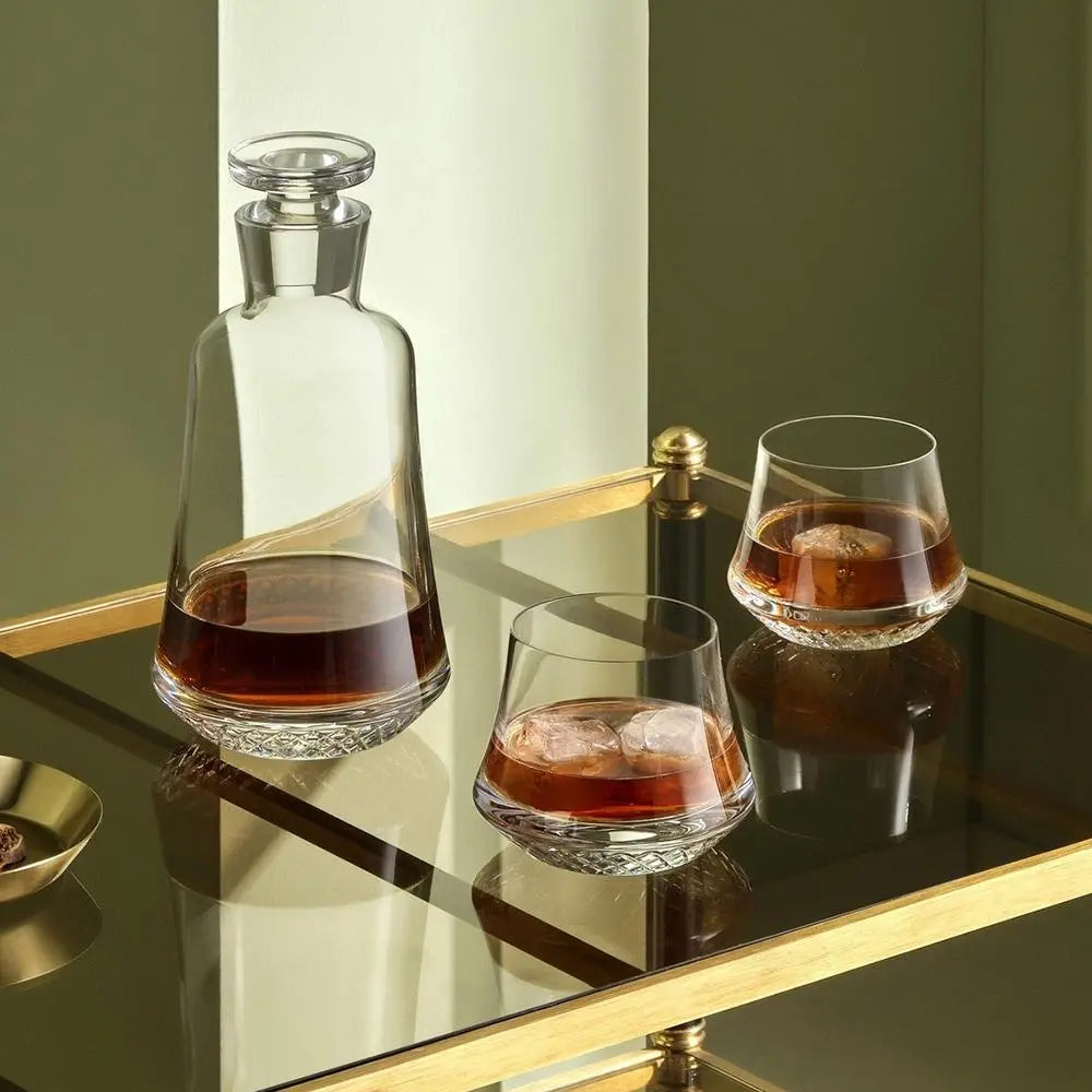 Ensemble de 2 verres de whisky SOF Paris posés sur une table en verre à côté d'une carafe de whisky. Le mur au fond est vert.