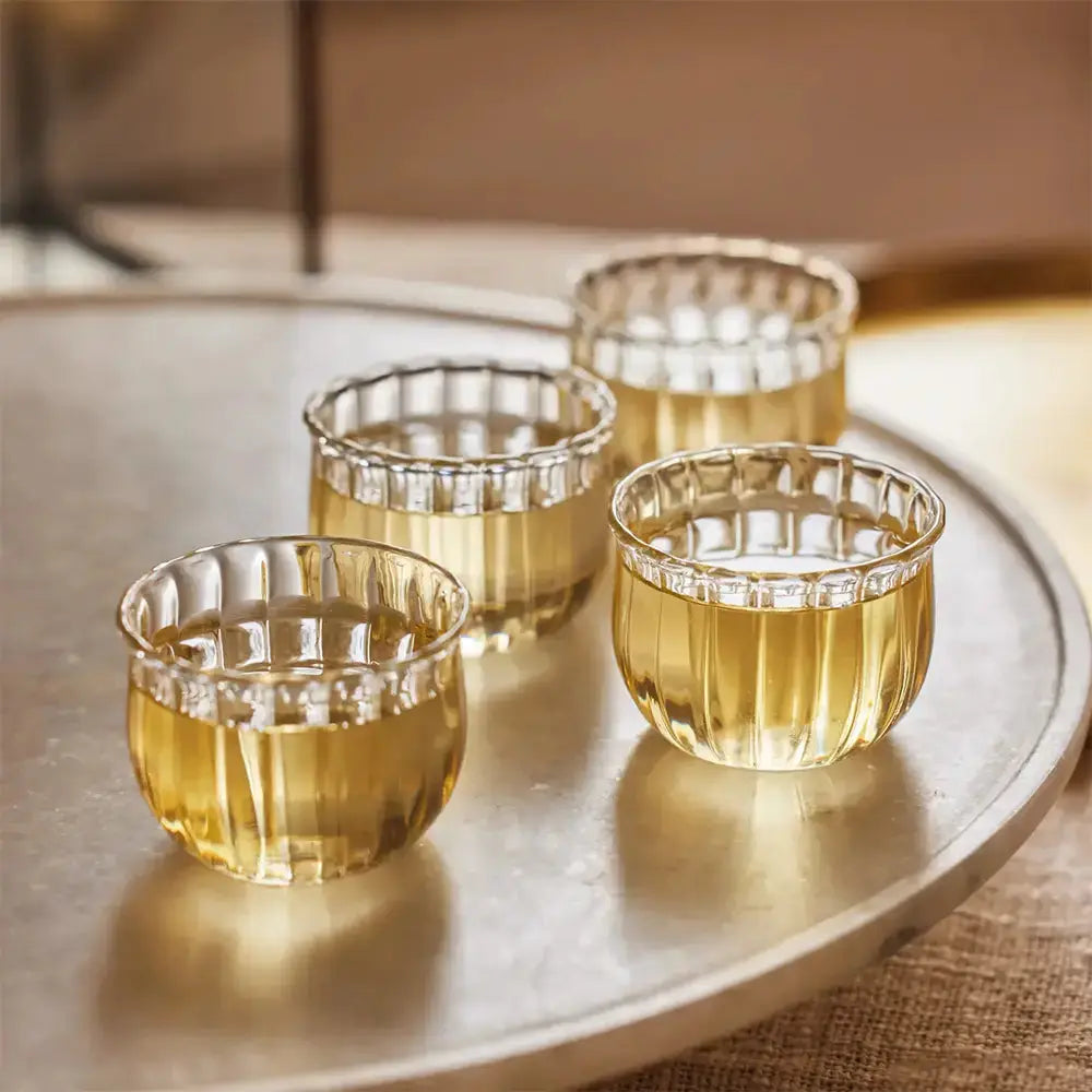 Lot de 4 tasses à saké posées sur une table en bois dans un cadre relaxant.