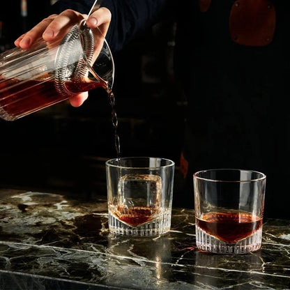 Set de 4 verres verres de whisky Caldera au comptoir d'un bar. Le barman est en train de servir un cocktail dans un des verres.