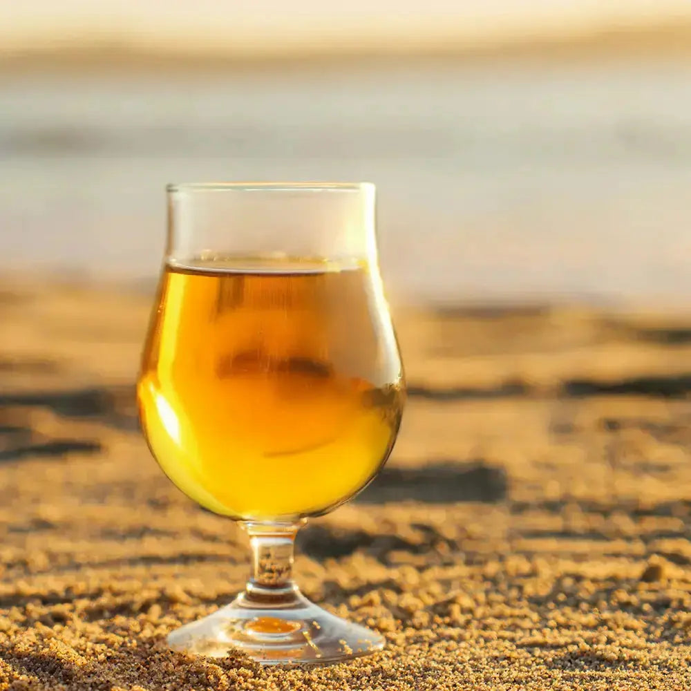 Verre de cidre tulipe sur une plage ensoleillée.